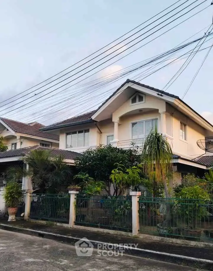 Charming two-story house with lush garden and classic architecture in a serene neighborhood.