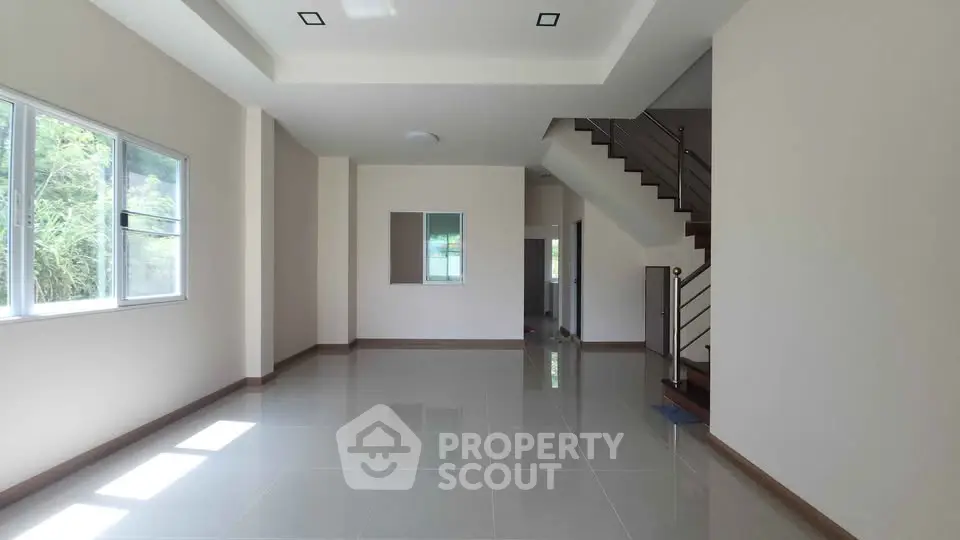 Spacious modern living room with large windows and sleek staircase