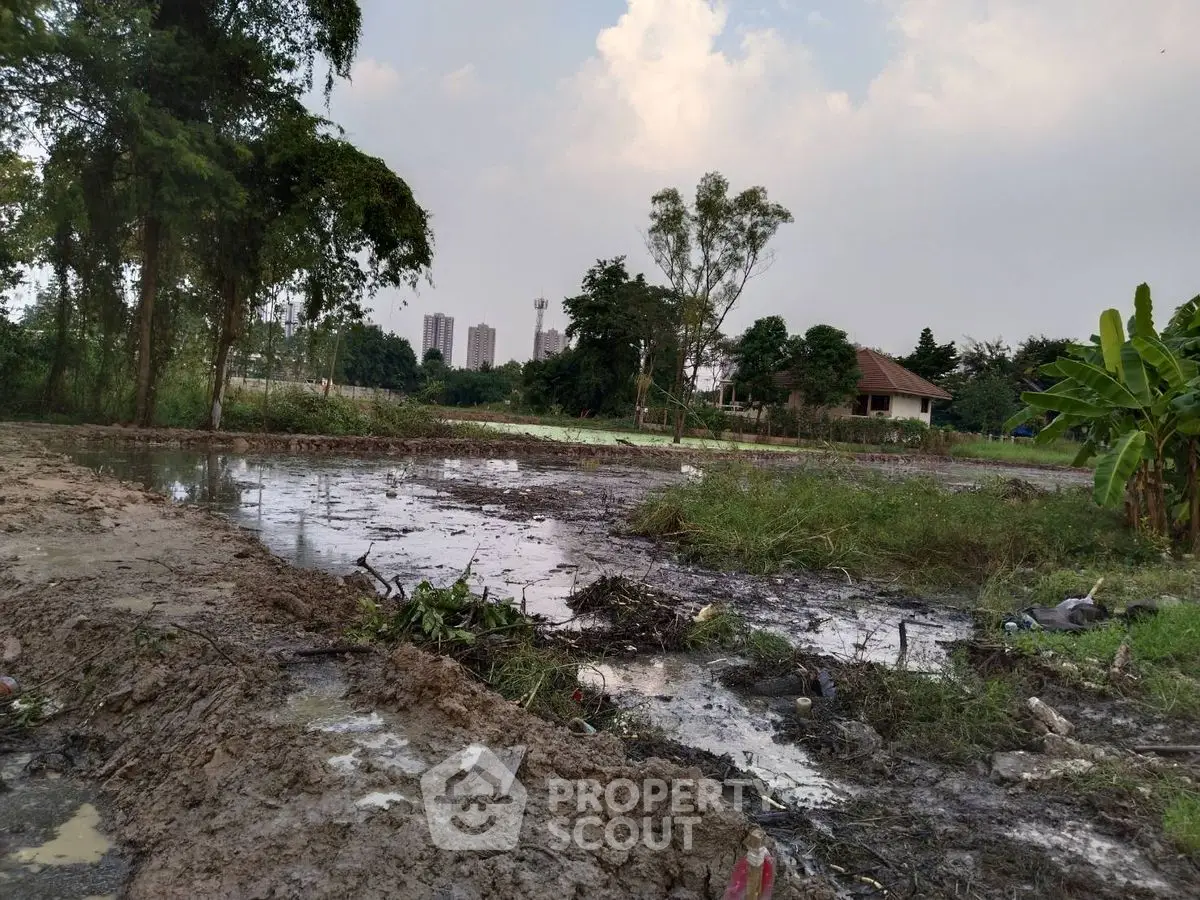 Vacant land with muddy terrain and distant city skyline, ideal for development opportunities.