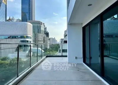 Spacious urban balcony with glass railing and city skyline view, perfect for relaxation and entertainment.