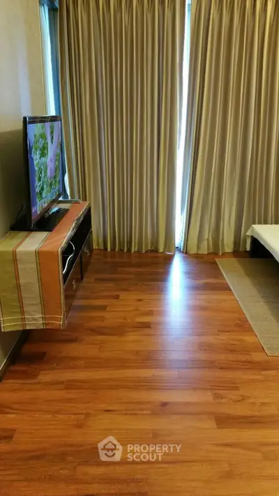 Cozy bedroom with wooden flooring and TV setup, perfect for relaxation.