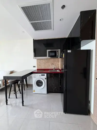 Modern kitchen with sleek black appliances and washing machine