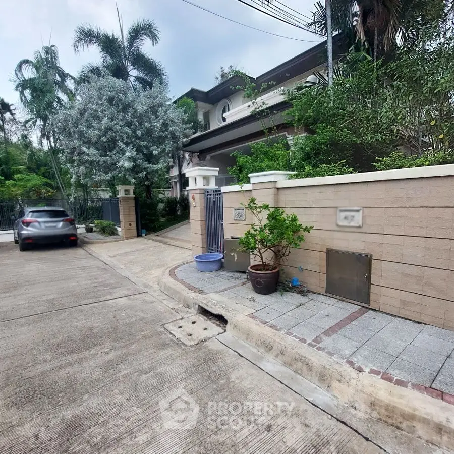 Charming suburban house with lush greenery and secure gated entrance.
