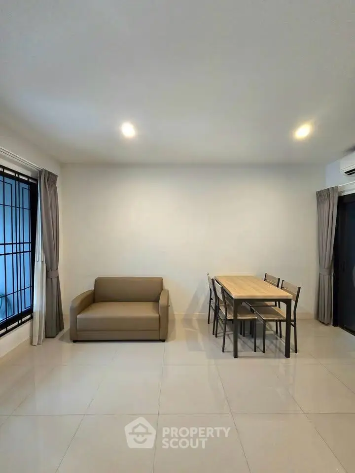 Spacious living room with modern sofa and dining set, perfect for family gatherings.