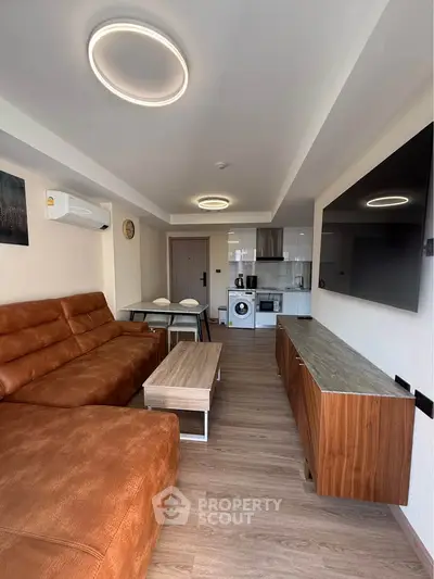 Modern living room with open kitchen, stylish furniture, and appliances in a cozy apartment.