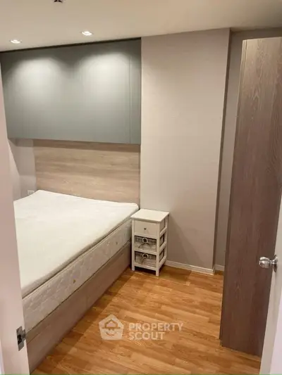 Cozy bedroom with wooden flooring and built-in storage, perfect for modern living.