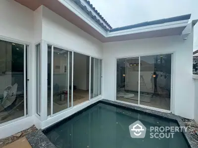 Modern home exterior with sleek sliding glass doors and a stylish small pool in a private courtyard.