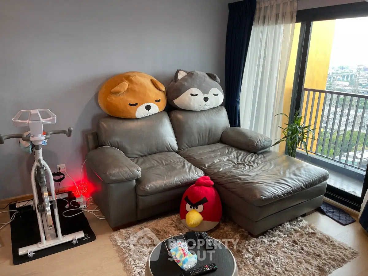 Cozy living room with plush sofa, balcony view, and exercise bike