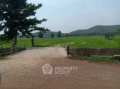 Scenic rural landscape with lush green fields and distant hills, perfect for real estate development.