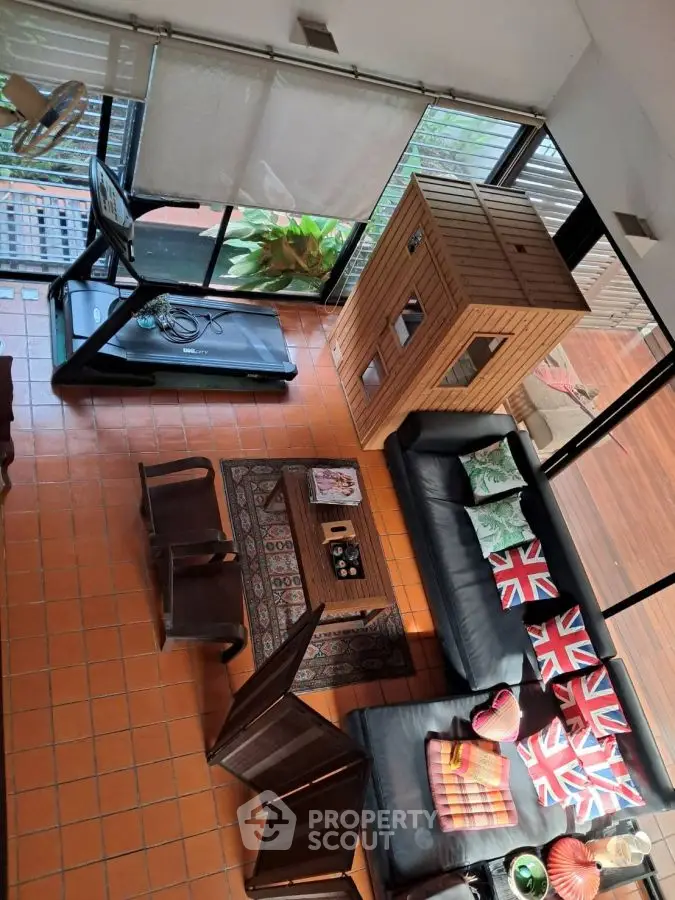 Spacious living room with treadmill and unique decor, featuring large windows and natural light.