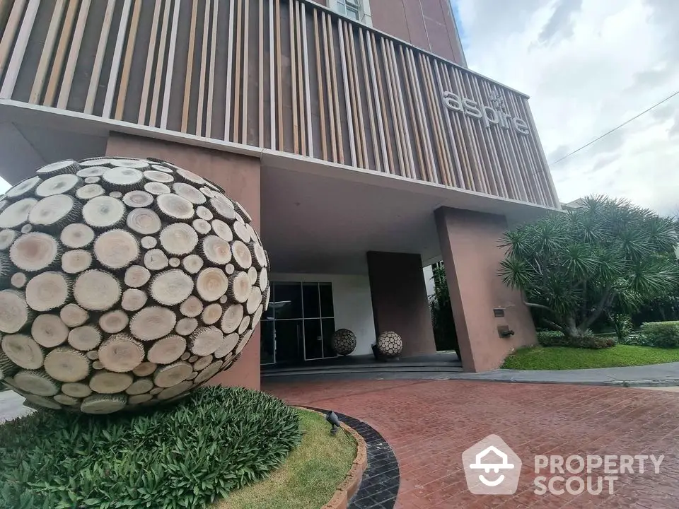 Modern building entrance with unique wooden sphere sculptures and lush landscaping