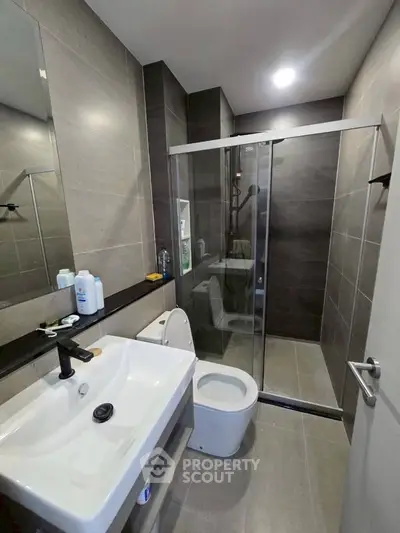 Modern bathroom with sleek design, featuring a glass shower enclosure and contemporary fixtures.