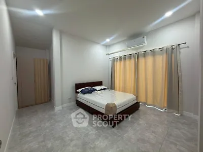 Spacious bedroom with modern design and ample natural light, featuring a comfortable bed and stylish decor.