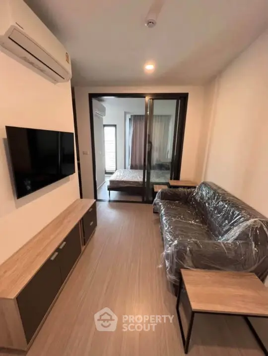 Modern living room with sleek furniture and view into cozy bedroom