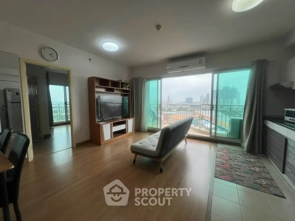 Spacious living room with modern decor and city view from large windows in a high-rise apartment.