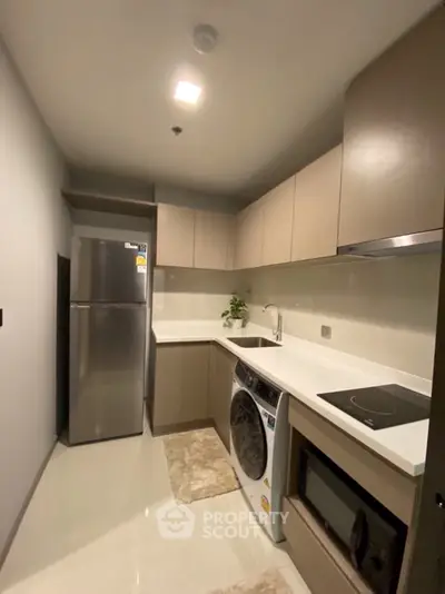 Modern kitchen with sleek cabinetry, stainless steel fridge, and built-in appliances in a compact layout.