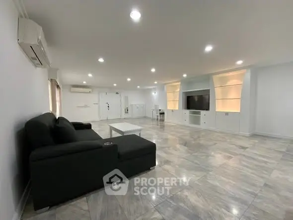 Spacious modern living room with sleek black sofa and built-in entertainment unit.