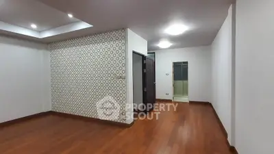 Spacious empty room with wooden flooring and modern lighting, ideal for customization.