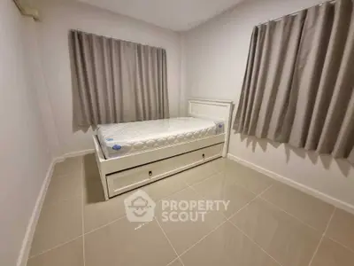 Minimalist bedroom with single bed and tiled floor, neutral curtains enhance serene ambiance.