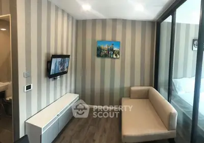 Modern living room with striped wallpaper, wall-mounted TV, and cozy beige sofa.