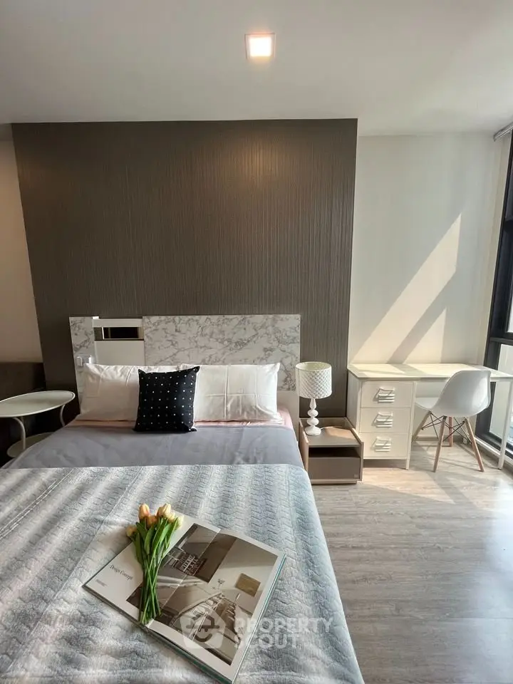 Modern bedroom with stylish decor, featuring a cozy bed, elegant side tables, and a bright workspace by the window.