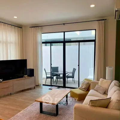 Modern living room with stylish furniture and large glass doors leading to a cozy patio.