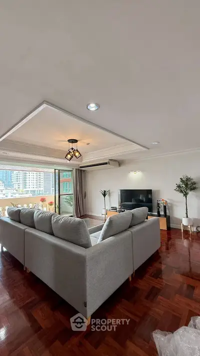 Spacious living room with modern decor and large windows offering city views.