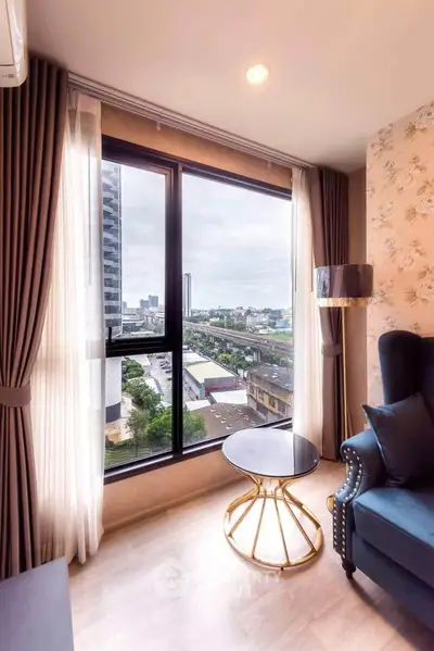 Chic modern living room with stunning city view through large window, elegant armchair, and stylish round table.