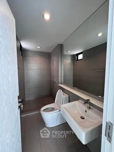Modern bathroom with sleek design, featuring a spacious shower and contemporary fixtures.