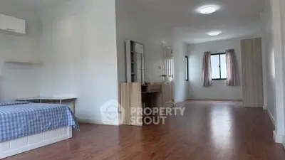 Spacious bedroom with wooden flooring and natural light in modern apartment.