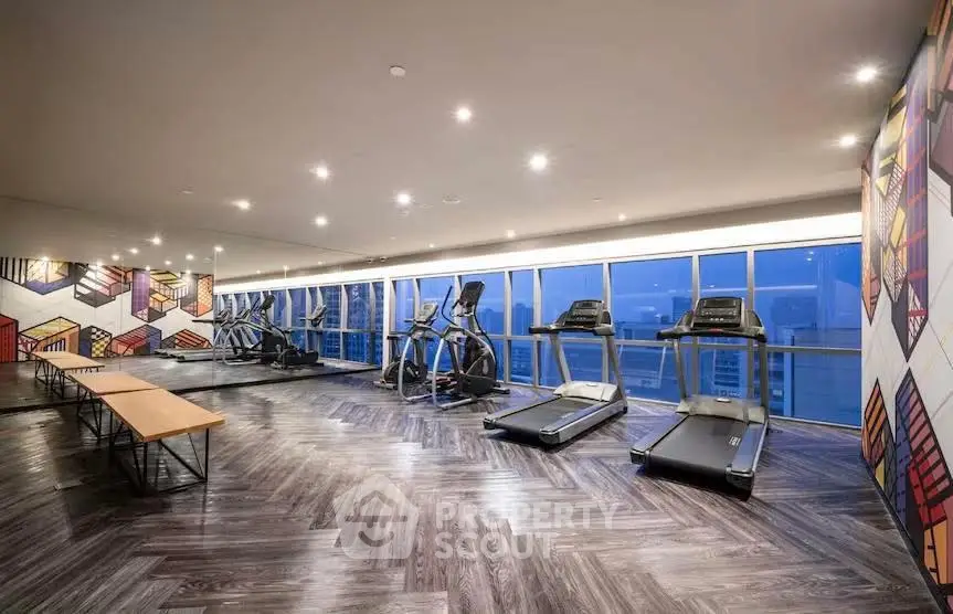 Modern gym with city view and stylish decor in luxury apartment building.