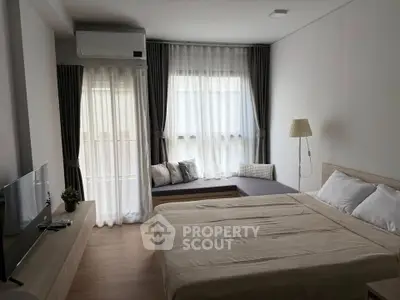 Modern bedroom with cozy seating area and natural light