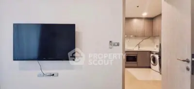 Modern apartment interior with wall-mounted TV and sleek kitchen appliances.