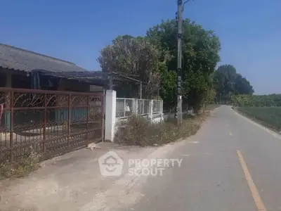 Charming rural property with gated entrance and lush greenery along a quiet road.