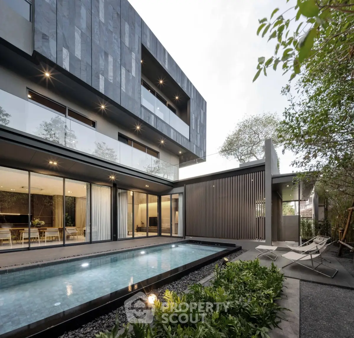 Modern luxury home with sleek architecture and private pool, surrounded by lush greenery.