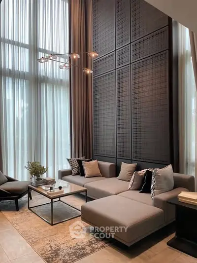 Luxurious high-ceiling living room with modern decor and floor-to-ceiling windows.