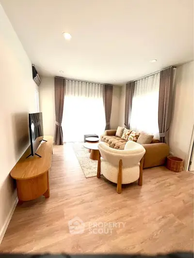Spacious living room with modern furniture and natural light, perfect for relaxation and entertainment.
