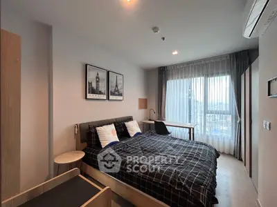 Modern bedroom with stylish decor and large window offering natural light.