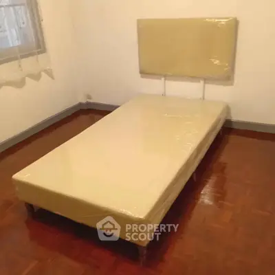 Minimalist bedroom with single bed and parquet flooring, perfect for cozy living.