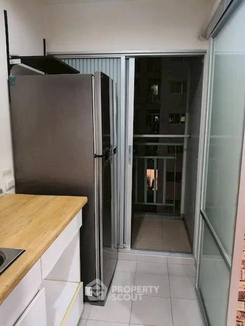 Compact kitchen with sliding glass doors leading to a small balcony.
