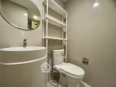 Modern bathroom with sleek fixtures and minimalist design, featuring a round mirror and compact storage.