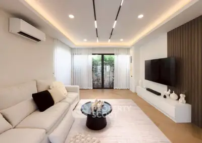 Modern living room with elegant decor, large sofa, and wall-mounted TV, featuring ambient lighting and stylish furnishings.