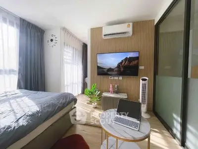 Modern bedroom with stylish decor, featuring a wall-mounted TV, air conditioning, and natural light.