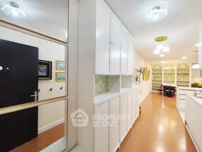 Spacious hallway with modern cabinetry and elegant lighting leading to a dining area.