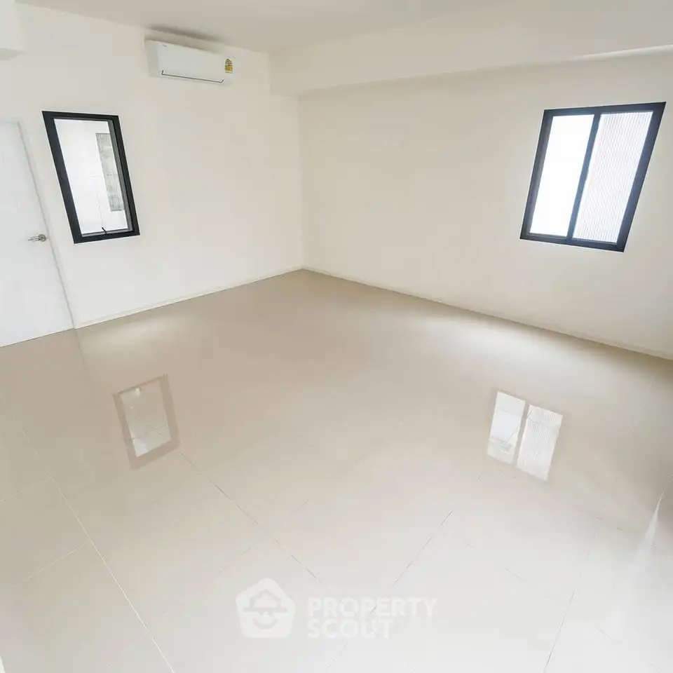 Spacious empty room with glossy tiled floor and large windows.