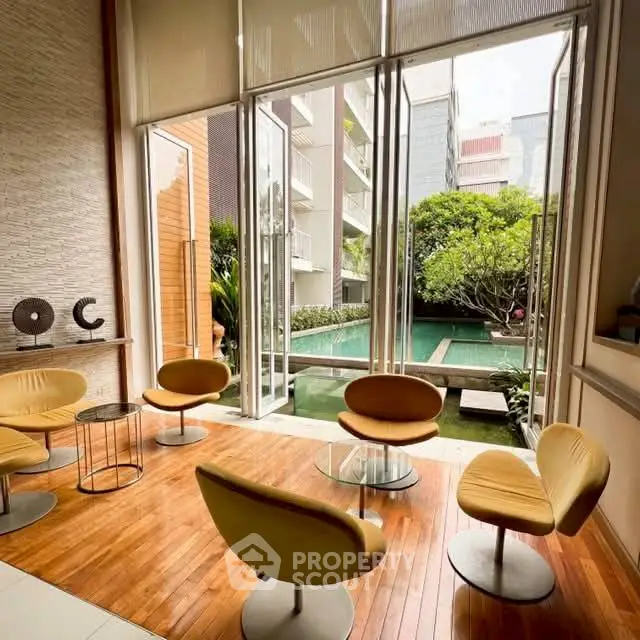 Luxurious modern lounge with pool view, featuring stylish seating and floor-to-ceiling windows.