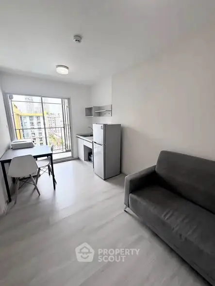 Modern studio apartment with sleek design and city view, featuring a compact kitchen and cozy living area.