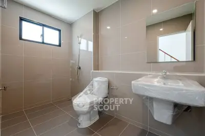 Modern bathroom with sleek fixtures and large tiles, featuring a spacious layout and natural light.