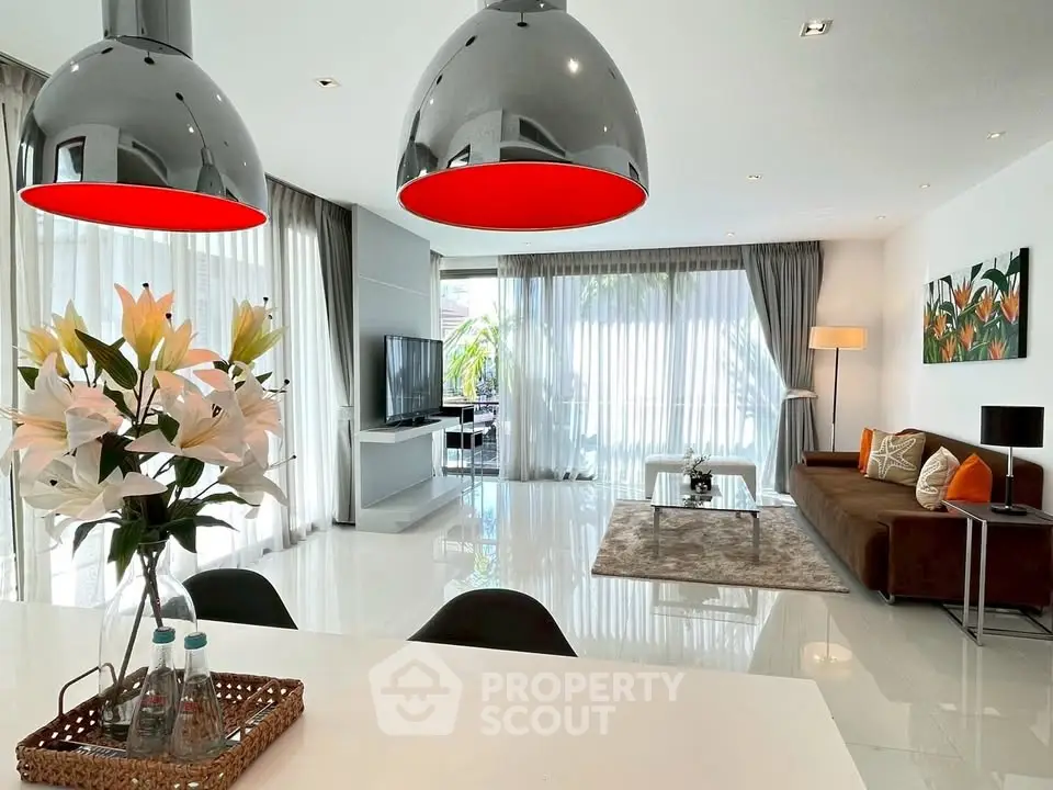 Modern living room with stylish decor and large windows, featuring elegant lighting and contemporary furniture.