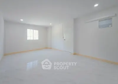 Spacious empty room with bright natural light and modern white tile flooring.